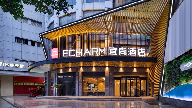 Ein moderner Hotel Eingang mit einer auffälligen Schilderung, Glastüren und einem überdachten Außenbereich.