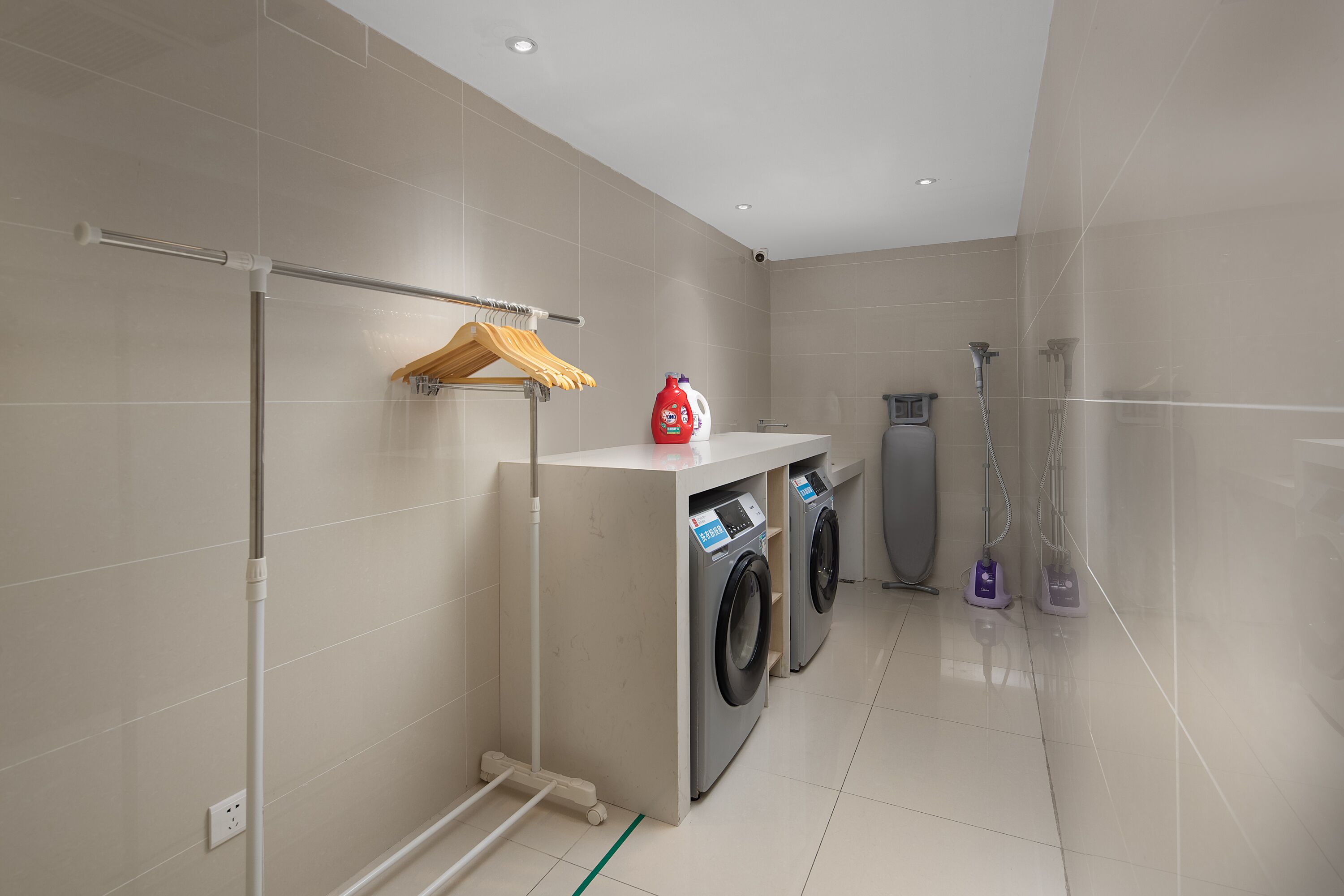 Une salle de bain moderne équipée d’un lave-linge, d’un sèche-linge et d’un espace douche.
