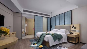 A modern hotel room with a large bed, bedside tables, a desk, and a mirror.