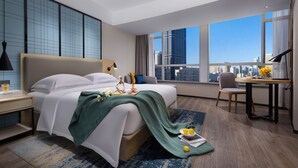Ein modernes Hotelzimmer mit einem großen Bett, einem Schreibtisch und Blick auf die Stadt.