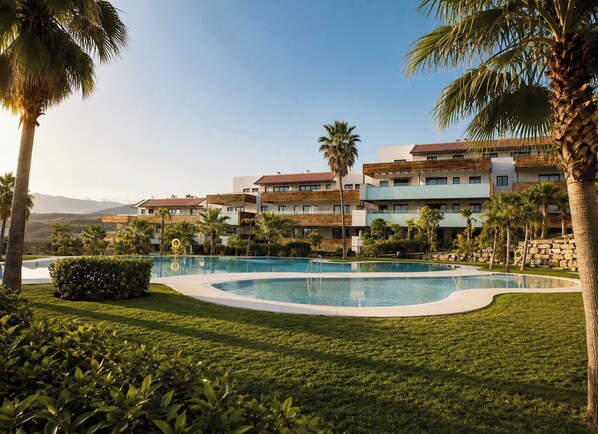 A resort with a swimming pool, palm trees, and multi-story buildings.