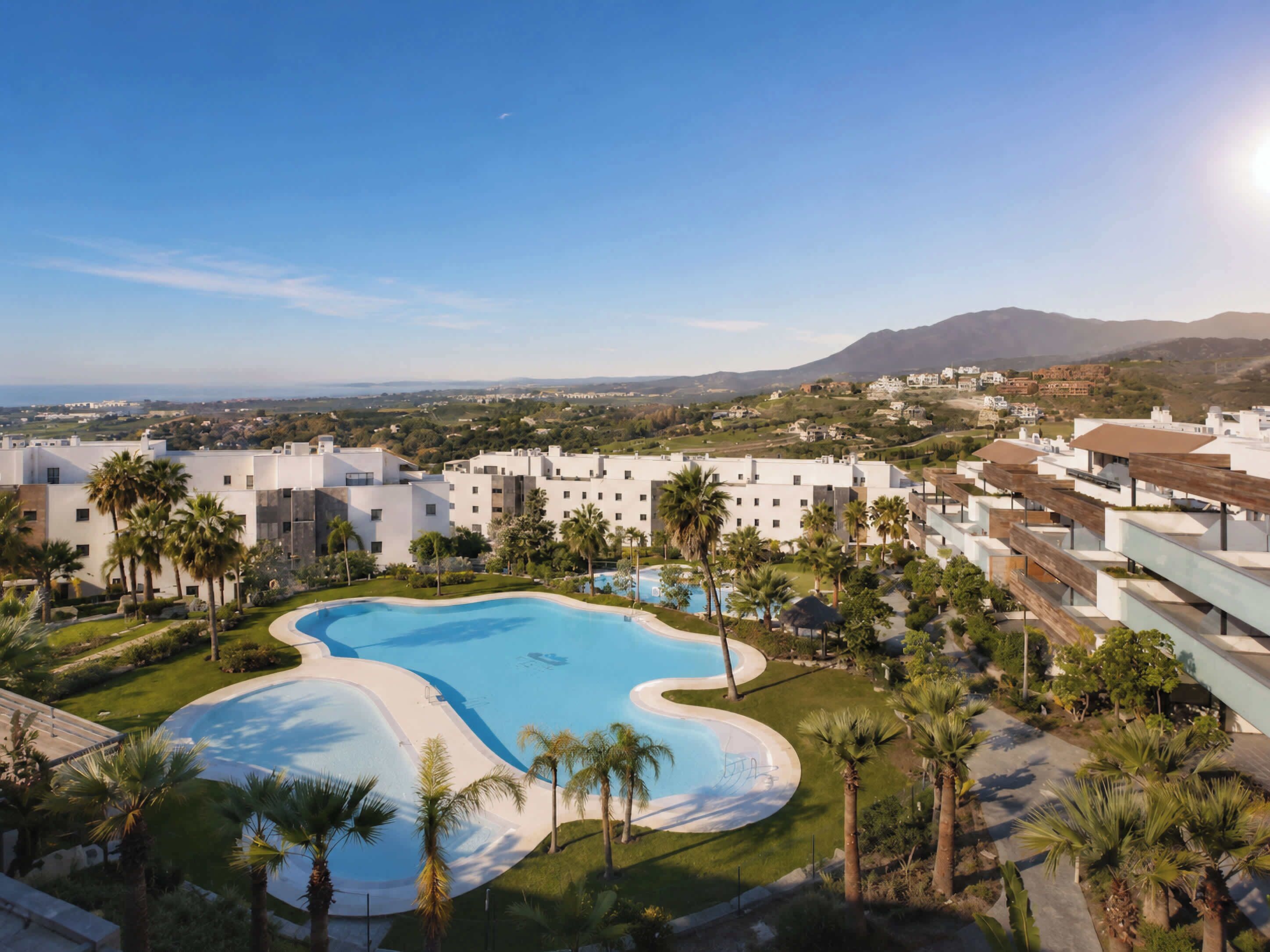 A resort with a swimming pool, palm trees, and a view of distant mountains.