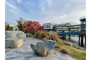 Stroll along the paved walkway to a serene body of water, surrounded by lush vegetation and a picturesque bridge.