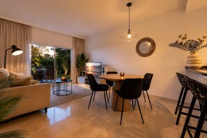 Ein modernes Wohnzimmer mit einer Couch, einem Esstisch, Stühlen und einem Fernseher.