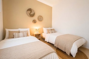 Un dormitorio con dos camas, una mesita de noche con lámpara y decoración en la pared.