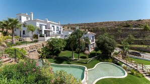 A modern villa with a swimming pool, surrounded by lush greenery and a clear view of the hillside.