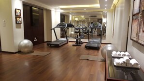 Une salle de remise en forme équipée de tapis de course, de ballons d’exercice et d’un murmiroir.