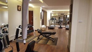 Une salle de sport équipée de matériel d’exercice, d’un tapis de course et d’un mur recouvert de miroirs.