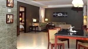 Une chambre d’hôtel comprenant un coin repas, un canapé, une télévision et un tableau accroché au mur.