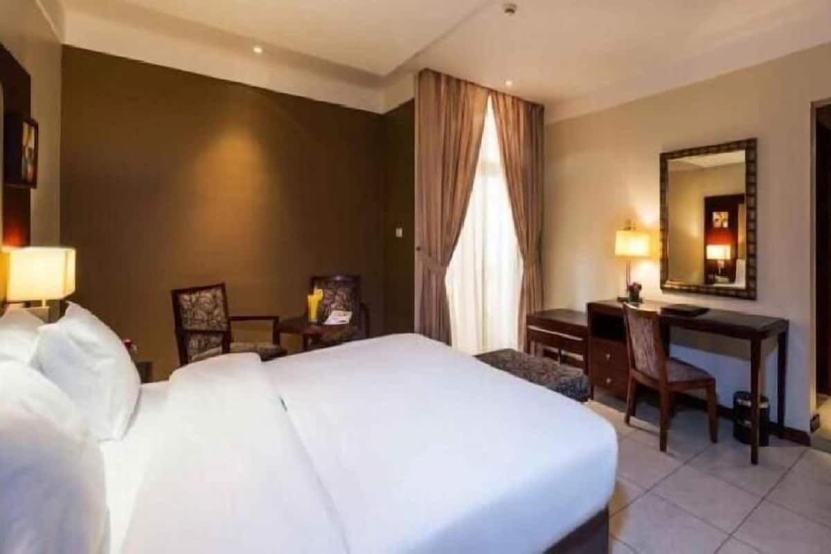 Une chambre d’hôtel équipée d’un lit, d’un bureau, d’une chaise et d’une armoire.