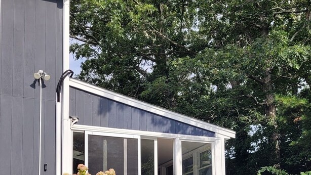 A swimming pool with a glass enclosure, surrounded by lush greenery and a modern building. - Cozy Cape Cod House - Stroll or Bike the Canal (Bourne)