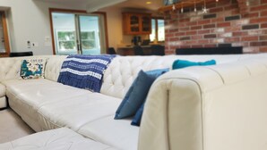 A white leather sofa with a blue and white patterned throw blanket and two blue pillows. - Cozy Cape Cod House - Stroll or Bike the Canal (Bourne)