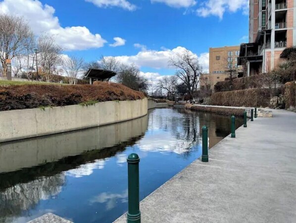 A calm water canal with a concrete walkway on one side and a building on the other.