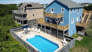 Uma casa grande com piscina, deck de madeira e vários níveis.