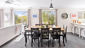 A dining area with a table set for four, surrounded by black chairs, a ceiling fan, and a pendant light.