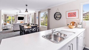 A modern kitchen with a large island, stainless steel sink, and a dining area with a table and chairs.