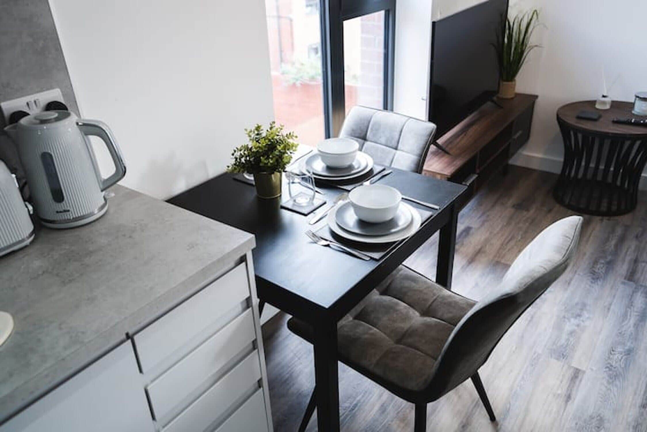 A modern kitchen with a dining area, featuring a kitchen island, a dining table set for two, and a comfortable seating arrangement.