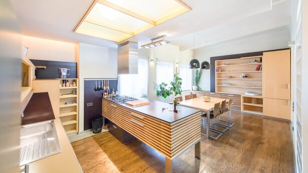 A modern kitchen with a central island, built-in shelves, and a dining area with chairs. - Venus Apartments - Parliament I (Budapest)