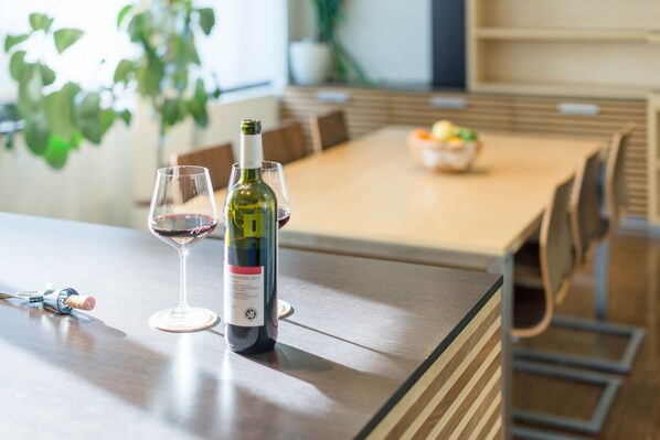 Una mesa de comedor con una botella de vino y una copa de vino tinto.