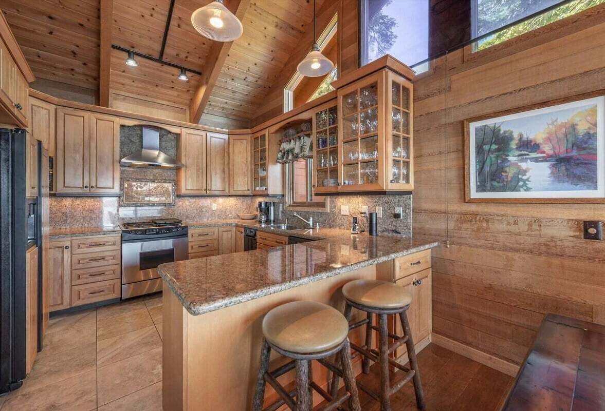 Une cuisine spacieuse avec des meubles en bois, un plan de travail en granit et un grand îlot central doté de tabourets.