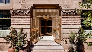 The entrance to The Quoin building with a stone facade, a metal gate, and potted plants. - The Quoin Hotel (Wilmington)
