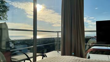 Un balcón con vista al paisaje urbano y el sol poniéndose tras las nubes.
