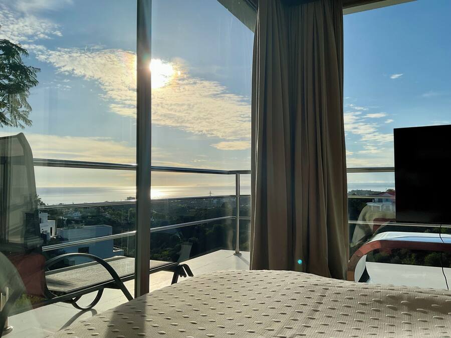 Un balcón con vista al paisaje urbano y el sol poniéndose tras las nubes.