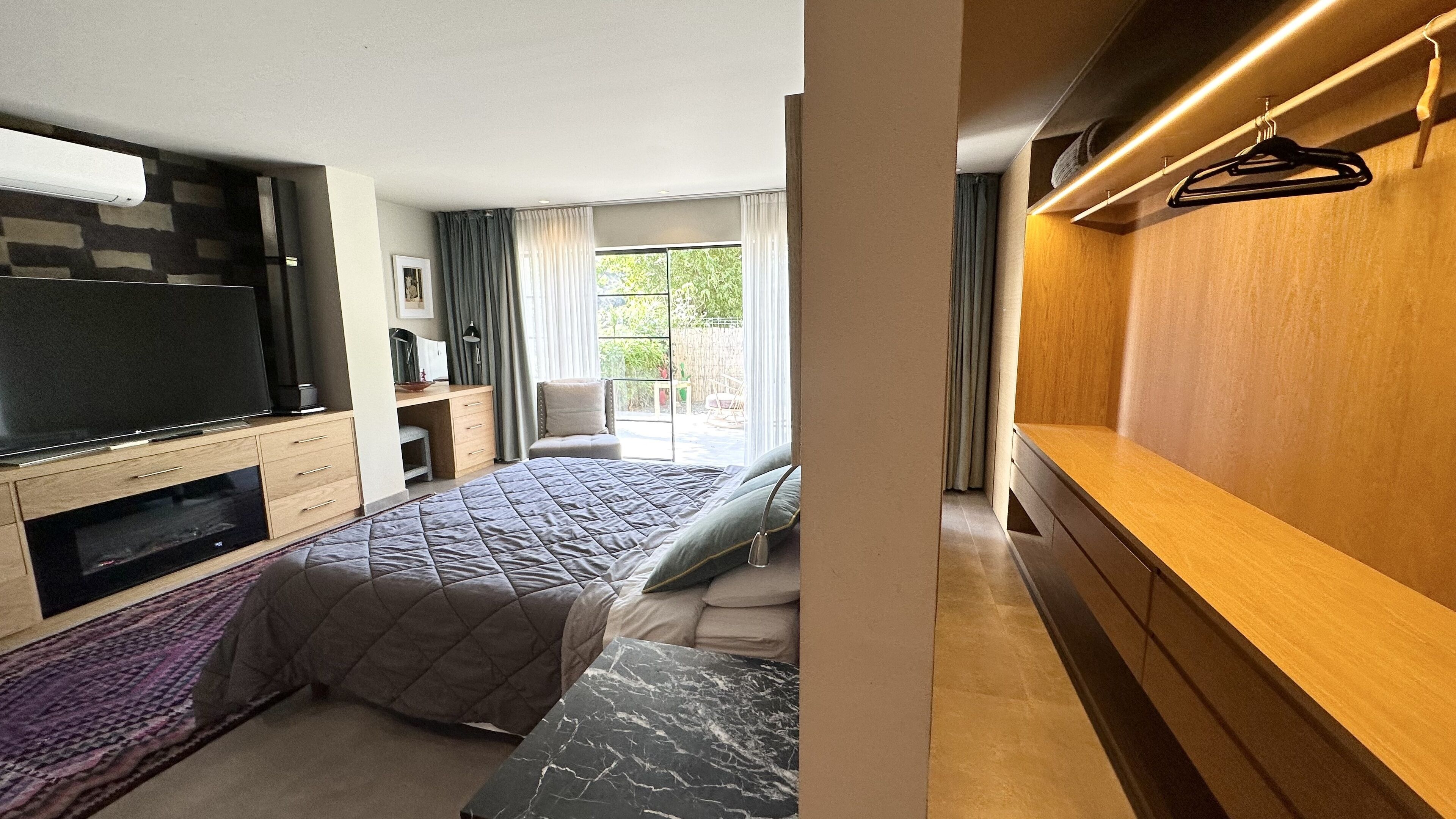 Une chambre moderne avec un grand lit, une télévision, un bureau et un dressing.