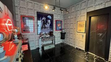 Una habitación con piso de mármol negro, un letrero de neón rojo y un cartel temático del espacio en la pared.