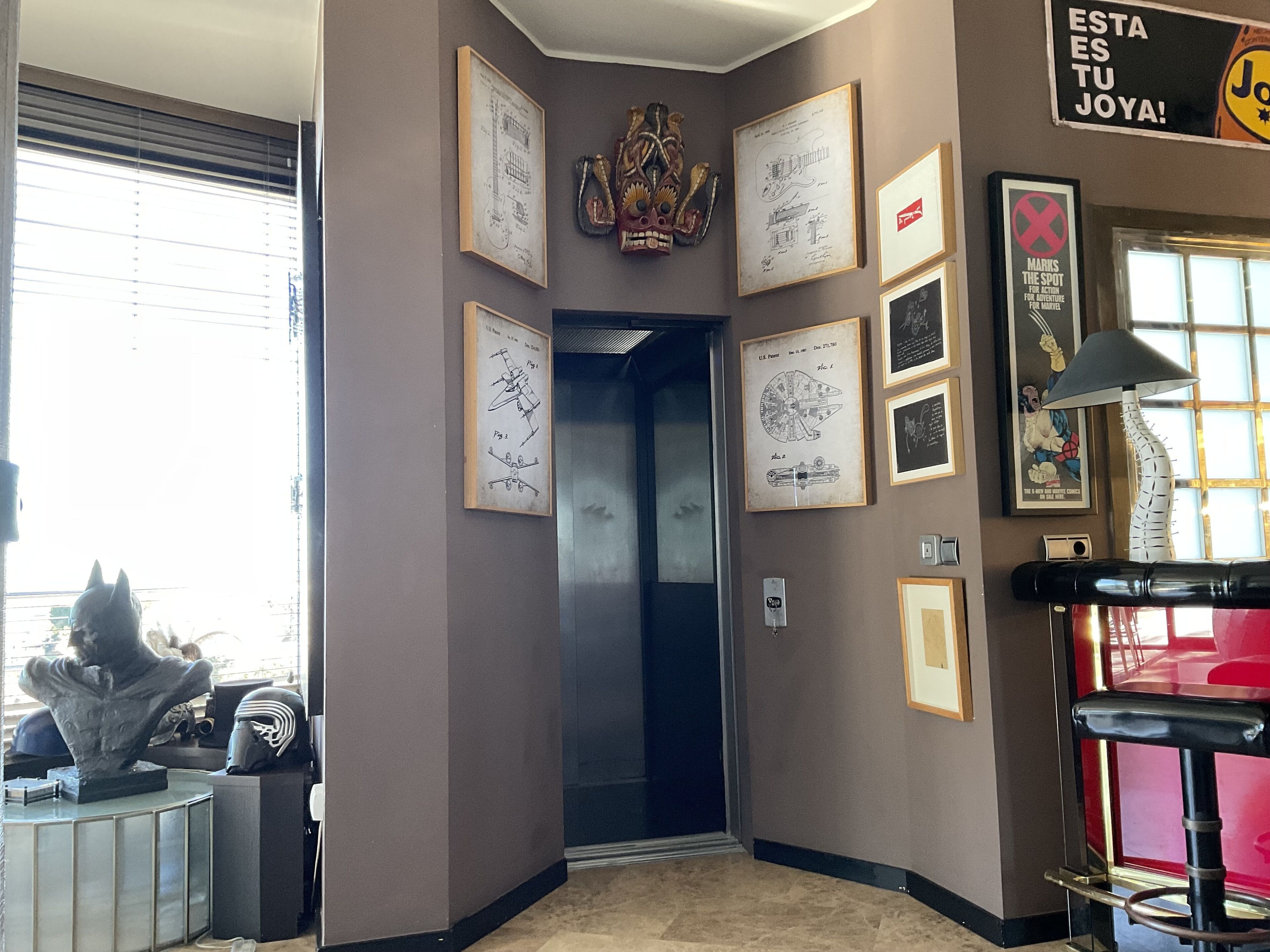 A hallway with framed drawings, a sculpture, and a Star Wars-themed sign.