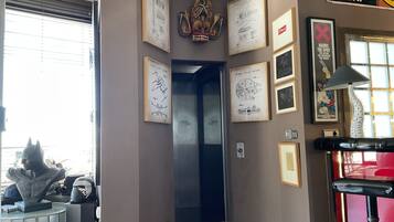 A hallway with framed drawings, a sculpture, and a Star Wars-themed sign.