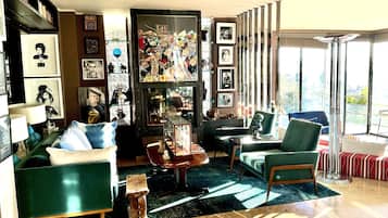 Un salon moderne avec un canapé vert, une table basse et une bibliothèque remplie de livres et de photos encadrées.