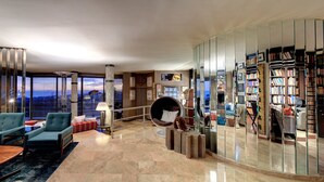 Una sala de estar moderna con un amplio ventanal, una zona de estar circular y una estantería llena de libros.