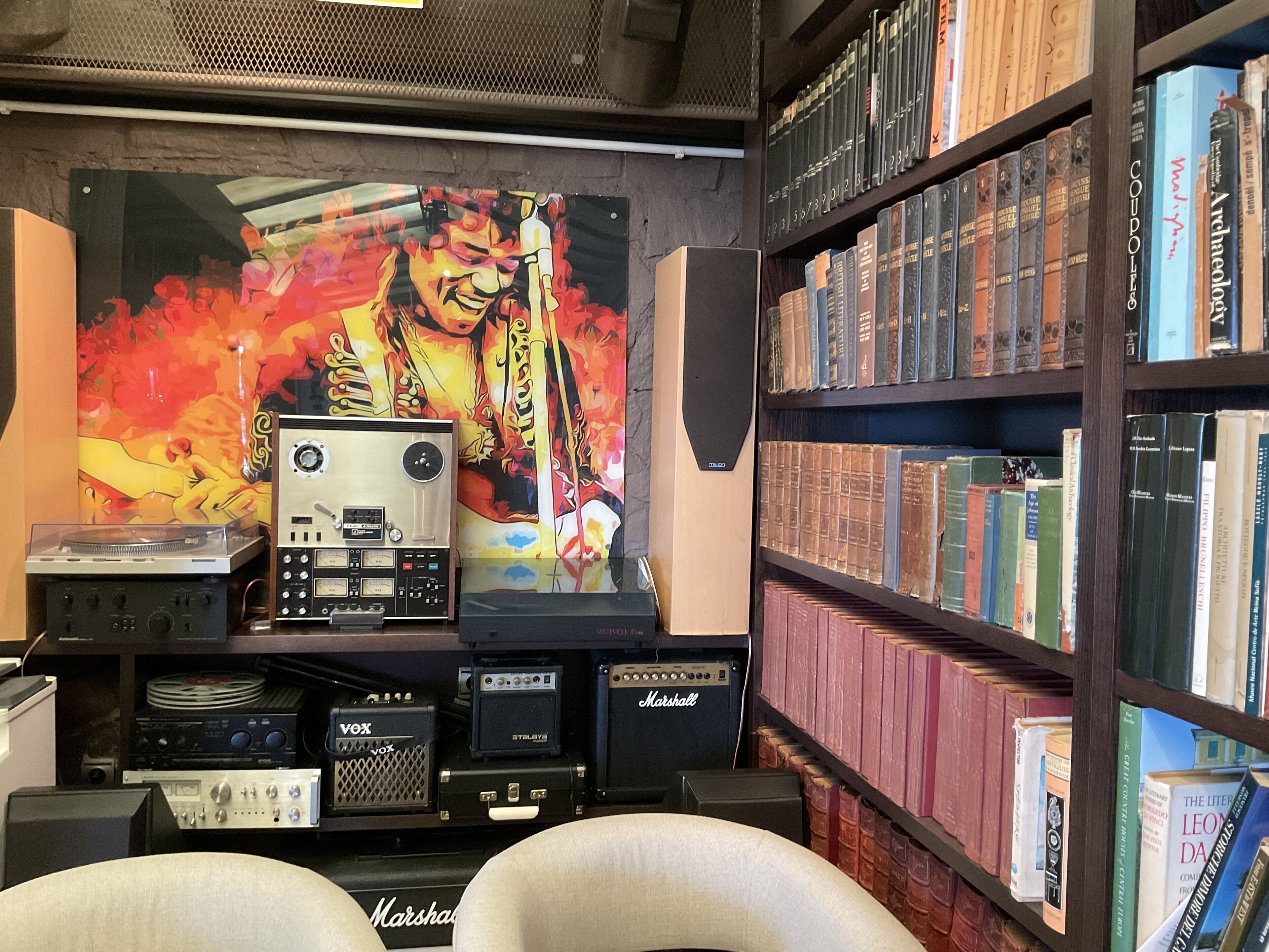 A room with a bookshelf filled with books, a turntable, and a vintage radio.