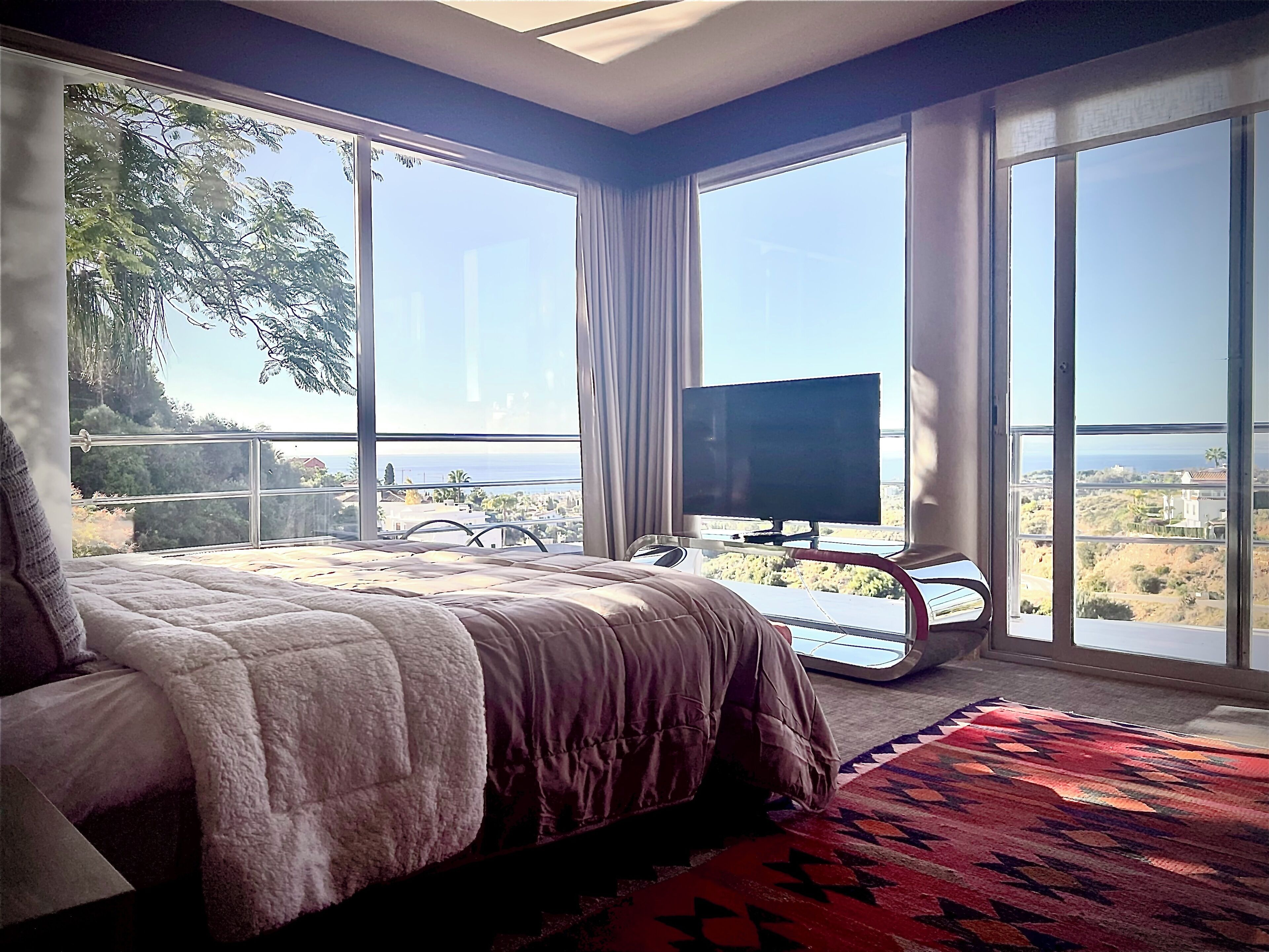 Un dormitorio con una cama grande, televisión y vista al mar.