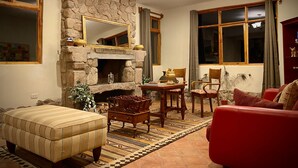 Un salon chaleureux avec une cheminée en pierre, des meubles en bois et de grandes fenêtres.