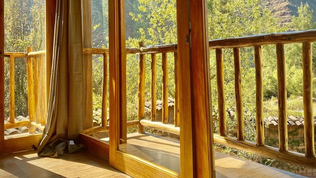 Une pièce en bois avec de grandes fenêtres et un balcon donnant sur un paysage montagneux.
