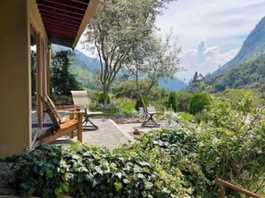 A patio with two lounge chairs, a stone pathway, and a view of a mountainous landscape. - Rejuvenate in our Cajas Biosphere paradise (Cuenca)