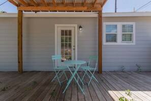 Eine überdachte Terrasse mit einer Holzw pergola, einer weißen Tür und einem kleinen Fenster.