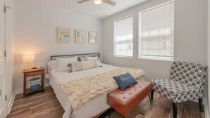 Una camera da letto con un letto, un comodino, una sedia e una ventola a soffitto.
