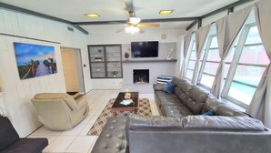 A living room with a sofa, a coffee table, a television, and a fireplace.
