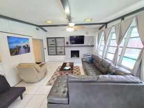Ein Wohnzimmer mit einer Couch, einem Couchtisch, einem Fernseher und einem Kamin.