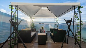 A covered outdoor seating area with wicker furniture and a view of the sea. - Vintage Dead Sea with Pool & Rooftop (Casablanca)
