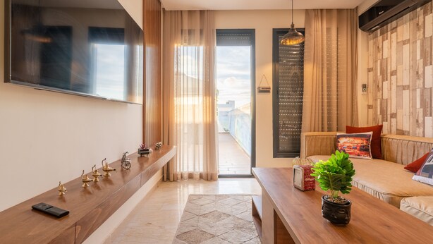 A modern living room with a sofa, a coffee table, a TV, and a balcony with curtains. - Vintage Dead Sea with Pool & Rooftop (Casablanca)