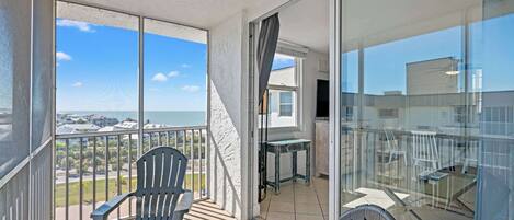 A balcony with two chairs, a table, and a view of the city.