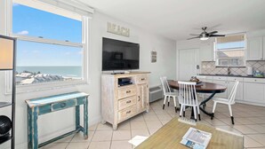 Eine moderne Küche mit Essbereich, einem Fernseher und Blick auf den Strand.