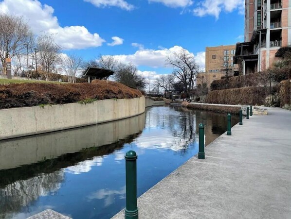 Stroll along the serene urban waterway, flanked by a pedestrian walkway and a concrete embankment.