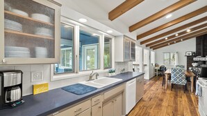 Una cocina moderna con una isla grande, electrodomésticos integrados y un comedor con una mesa y sillas de madera.