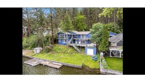 Una casa azul con un muelle a orillas de un río, rodeada de árboles.