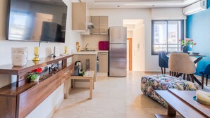 Eine moderne Küche mit großem Fernseher, einem Kühlschrank und einem Essbereich mit Stühlen und Tisch.